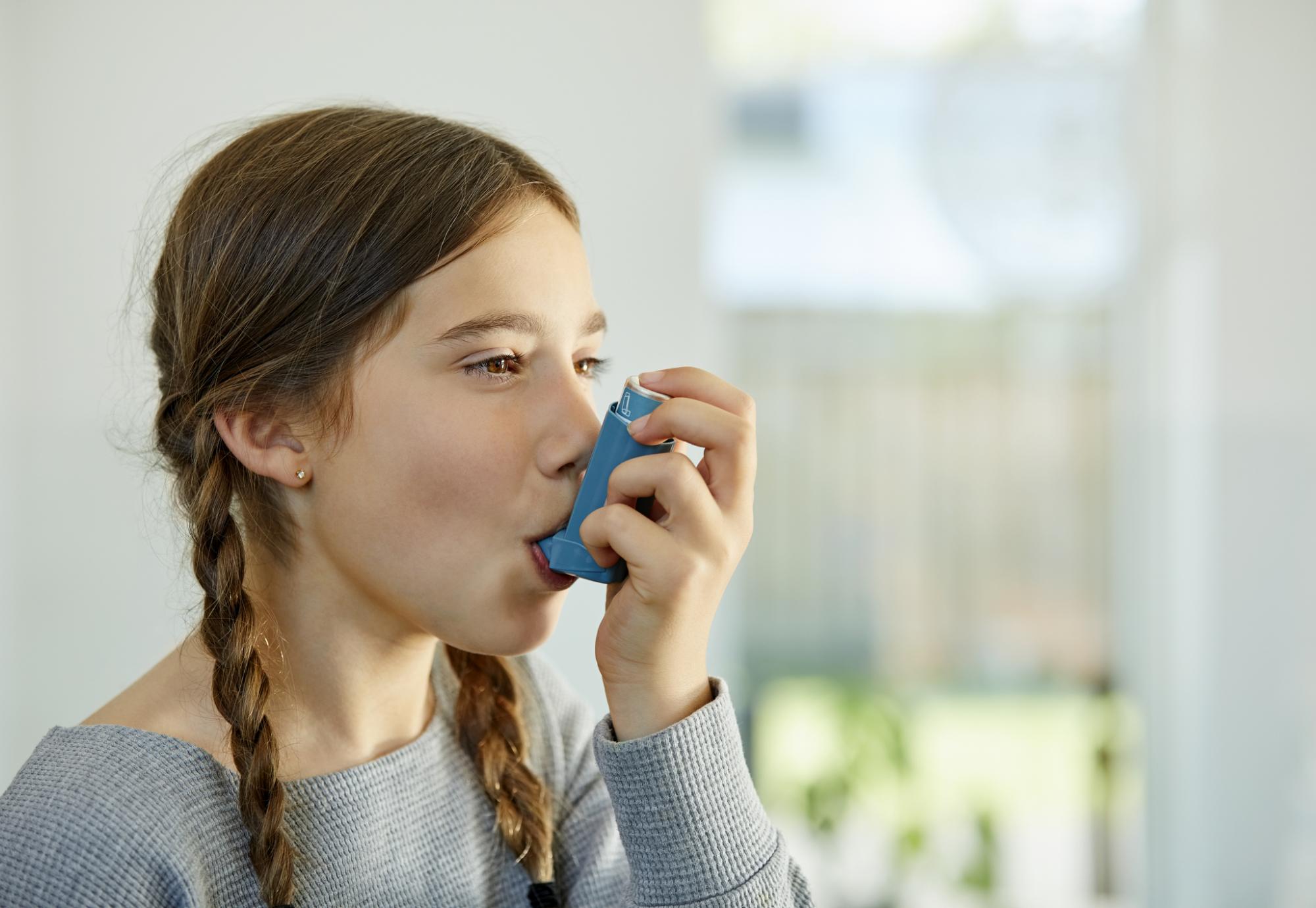 Young girl using asthma inhaler