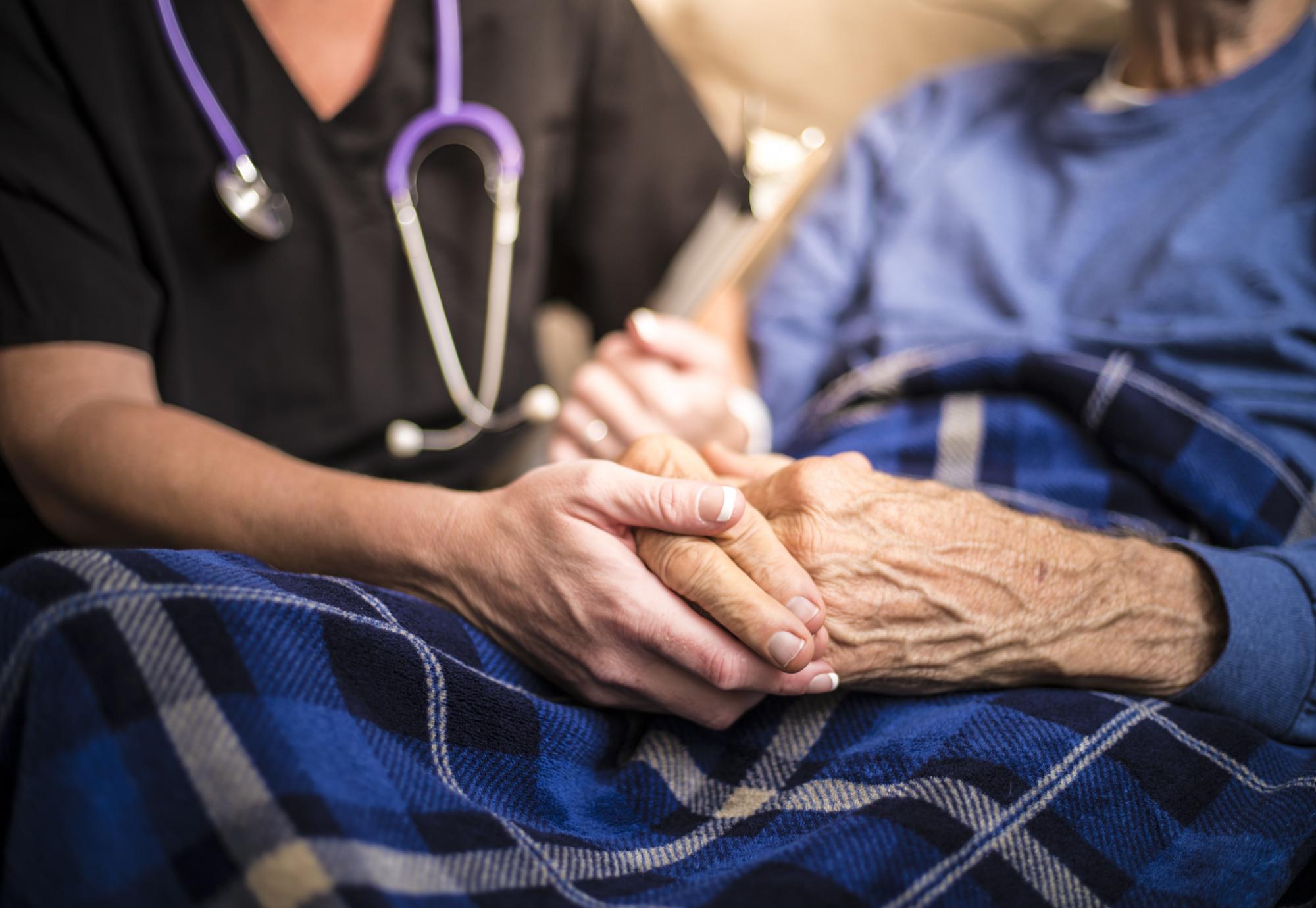 Nurse holding hand of elderly patient