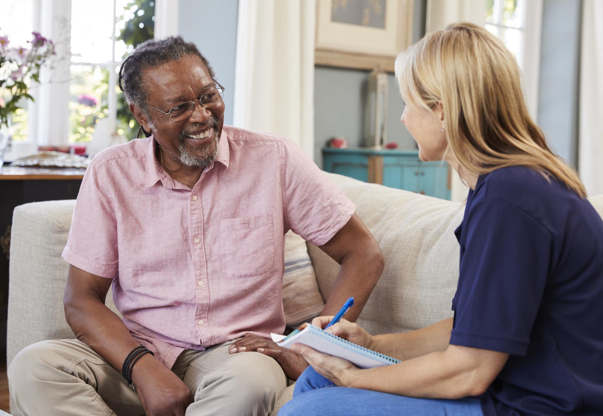 Female support worker talking with older male resident