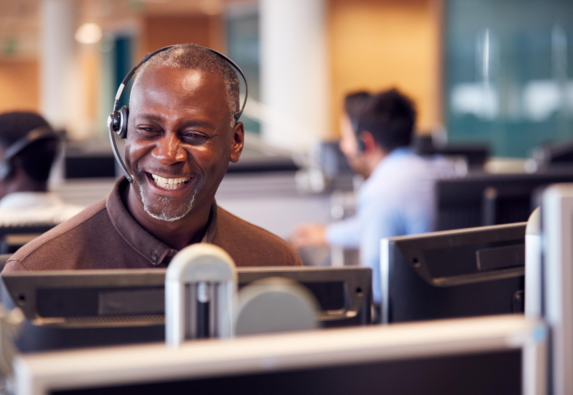 Smiling man operating a headset in a call centre environment