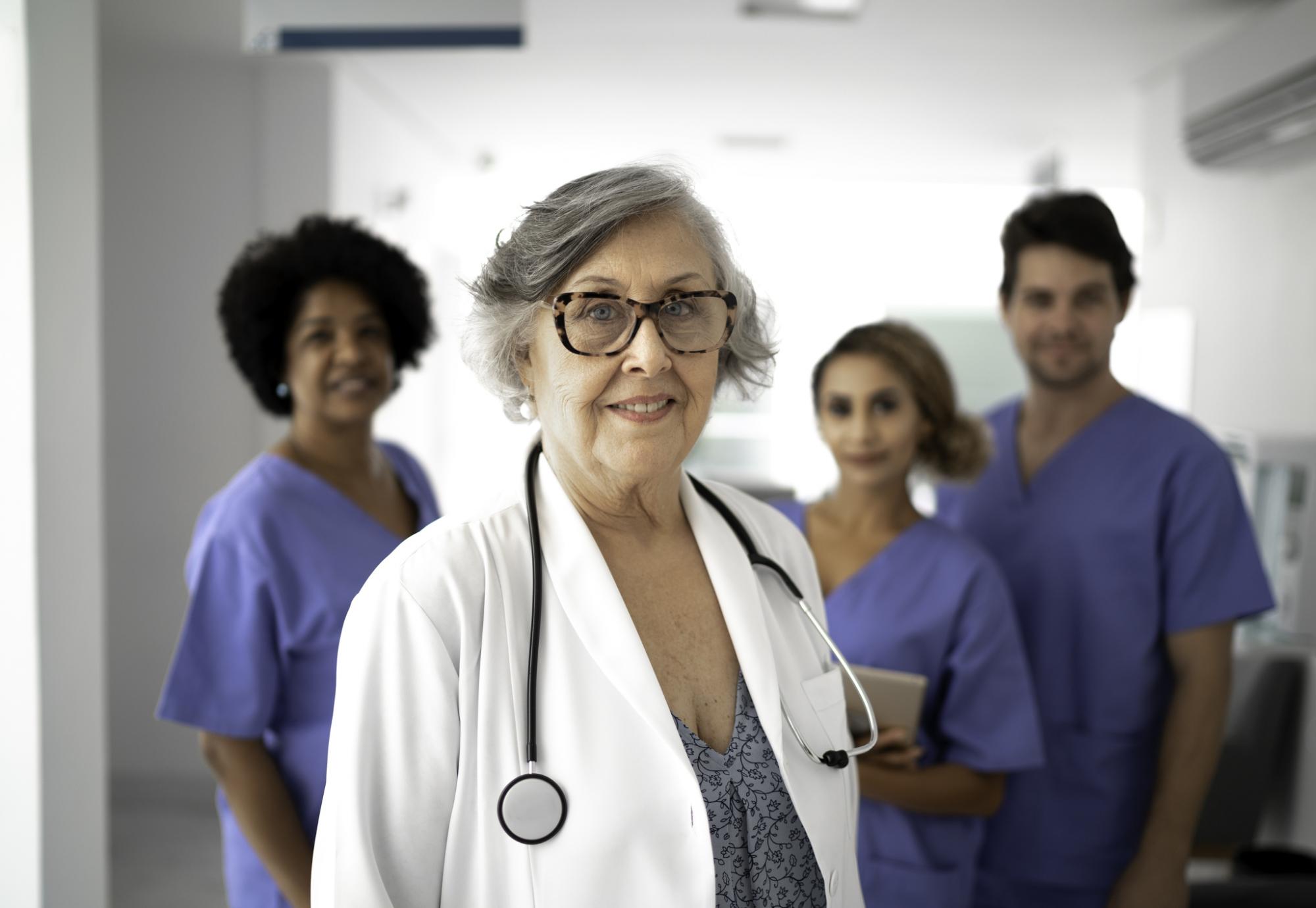Retired doctor standing in front of younger health colleagues
