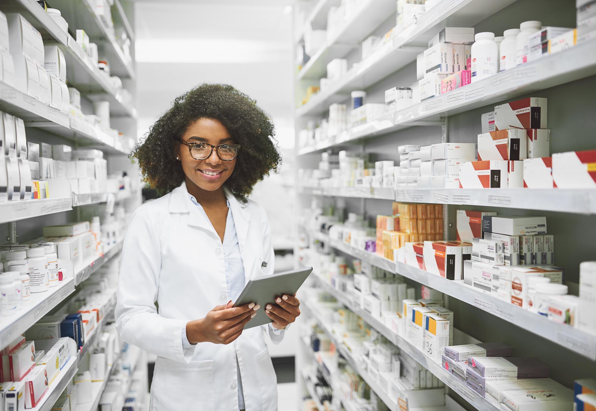 Young female pharmacist standing in an aisle of pharmaceuticals