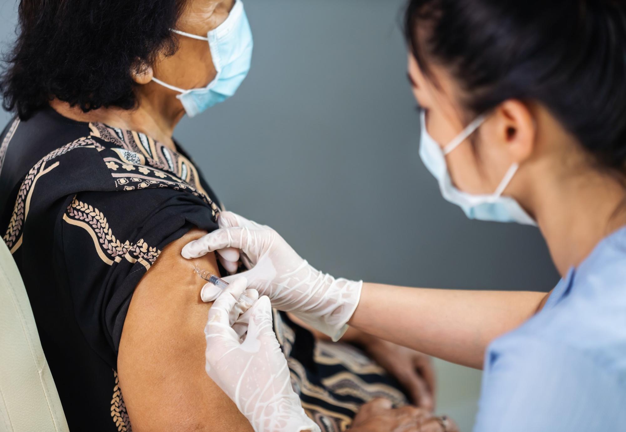 Health professional administering vaccine jab to a patient