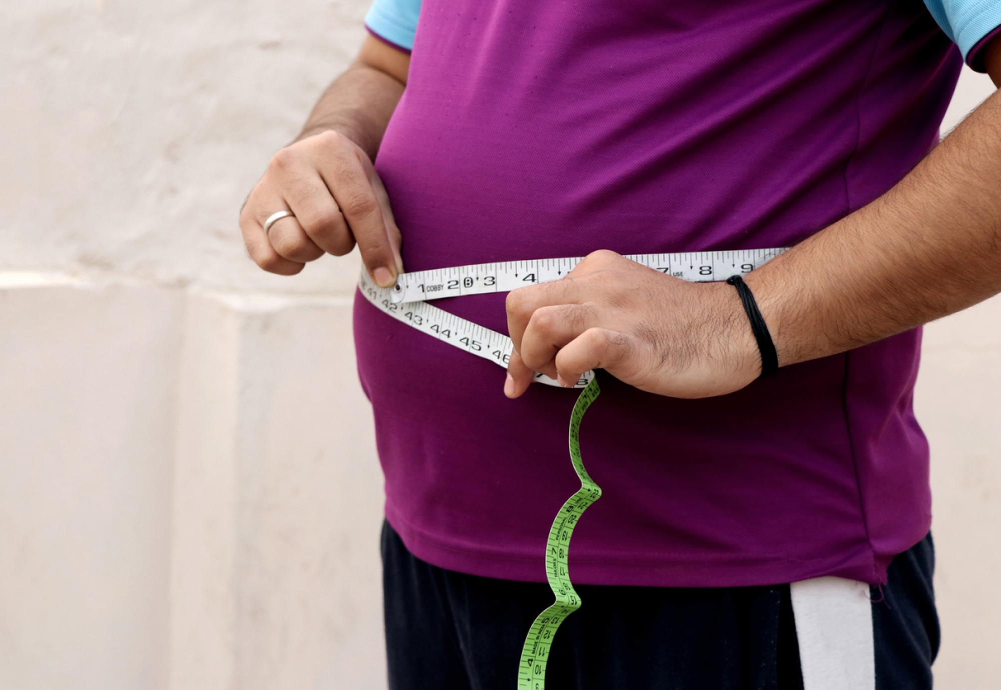 Obese person with a tape measure round their waist