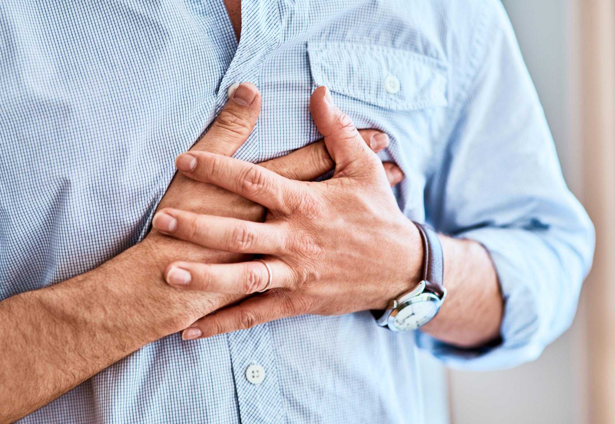 Man clutching his chest because of heart attack symptoms