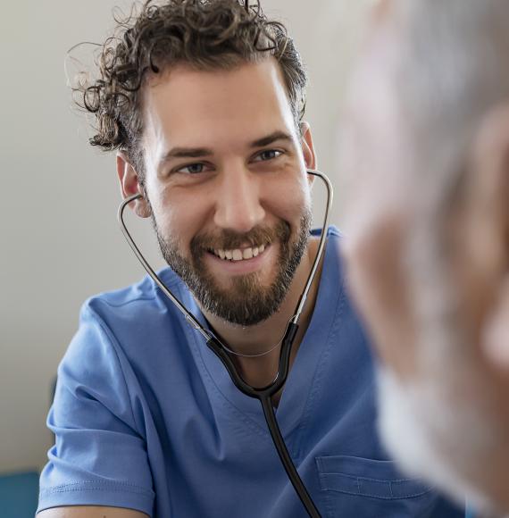 Male health professional listening to patient with stethoscope
