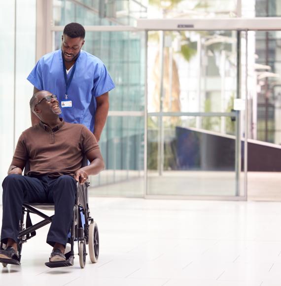 Male hospital porter transporting male patient in a wheelchair