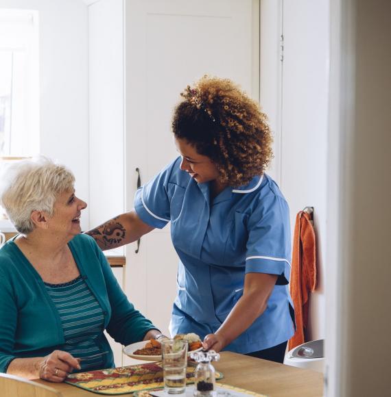 Social care professional supporting an elderly woman in her home