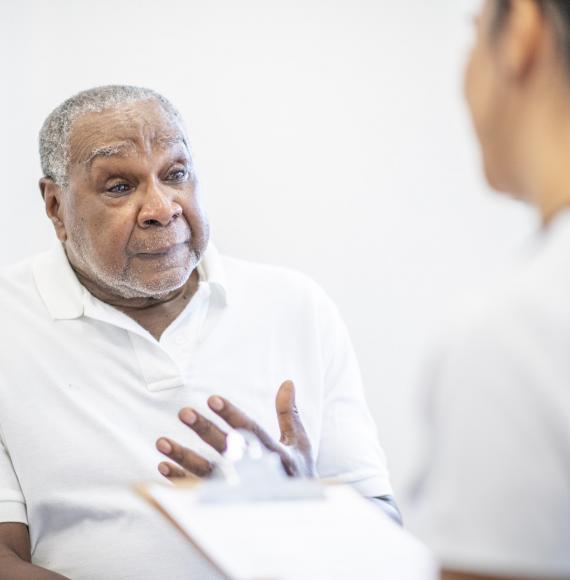Elderly male patient discussing symptoms with a health professional
