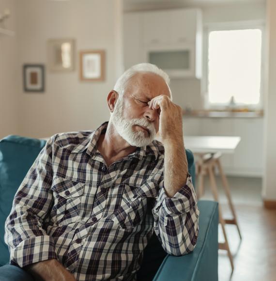 Older man holding his head with a migraine