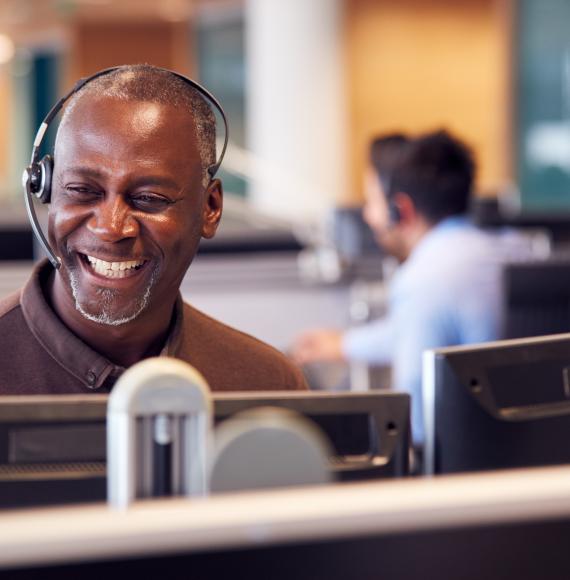 Smiling man operating a headset in a call centre environment