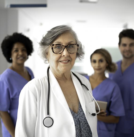 Retired doctor standing in front of younger health colleagues