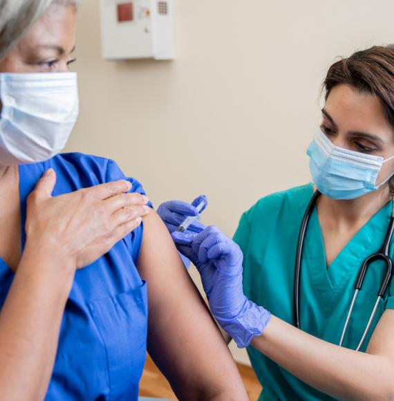 Nurse administering a vaccine to a colleague