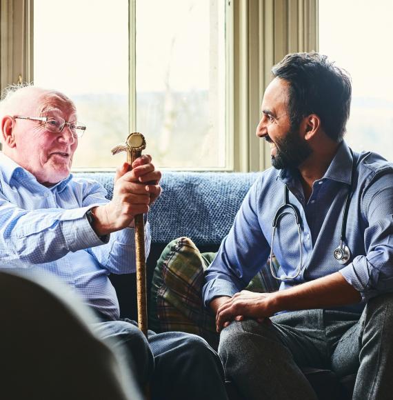 Elderly man with a cane talking with a male doctor
