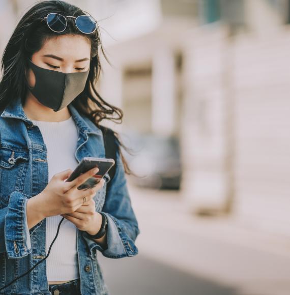 Young woman with a face mask using her phone