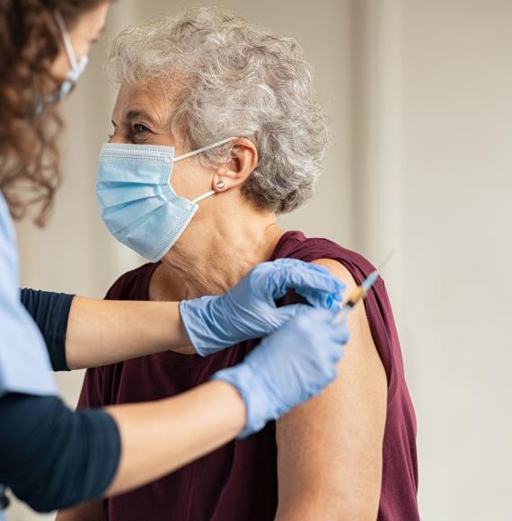 Elderly woman receiving a vaccine jab from a nurse