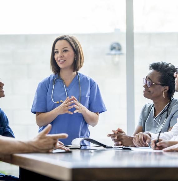 Female medical professional presenting to colleagues in a meeting