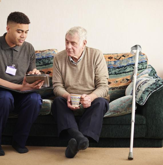 Social care worker supporting an elderly male patient