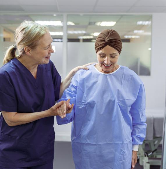 urse assisting female cancer patient walk through hospital ward 