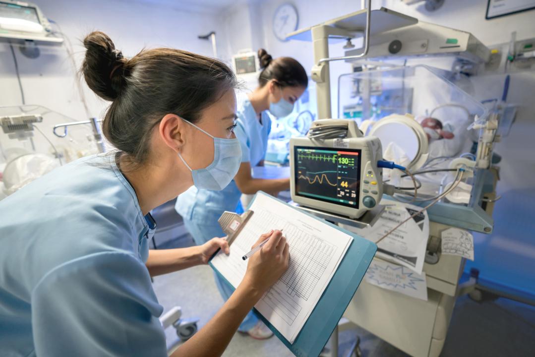 Nurse in a face mask talking notes from a machine