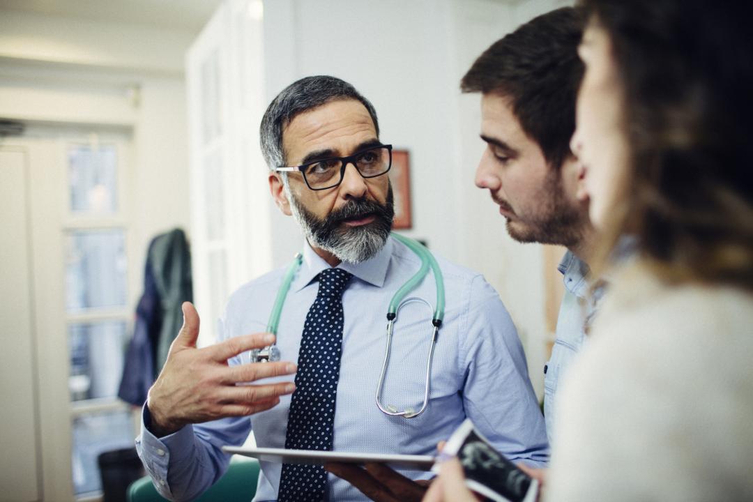 Doctor talking with colleagues while holding an iPad