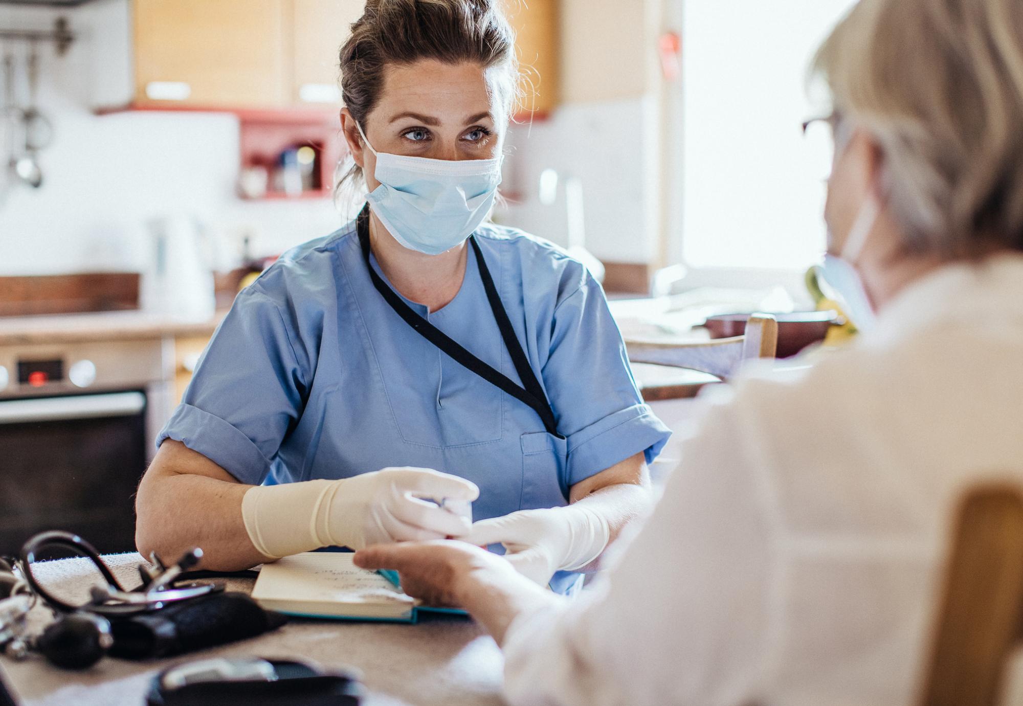 Female nurse in mask providing care in the community