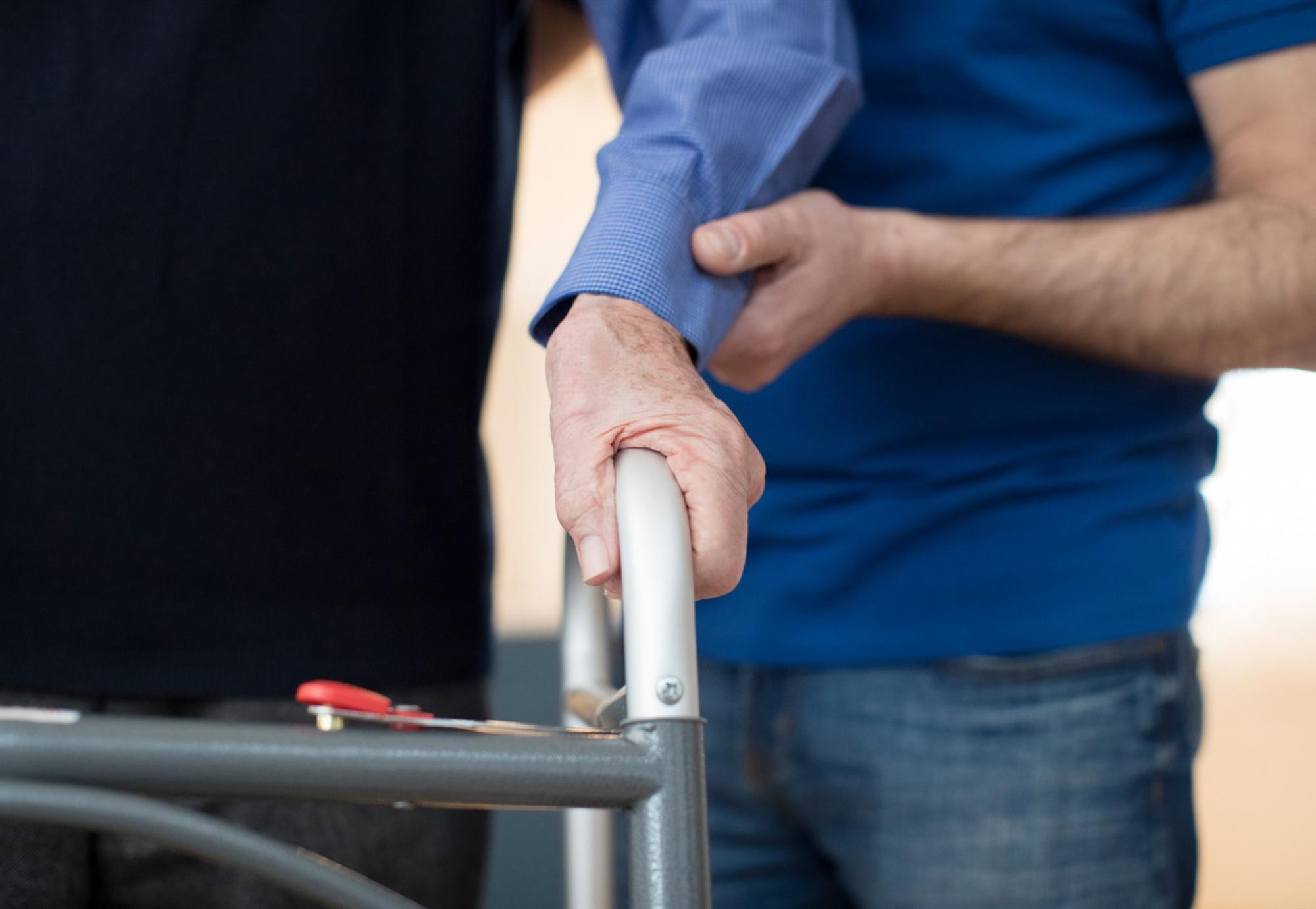 Hand supporting elderly man frame