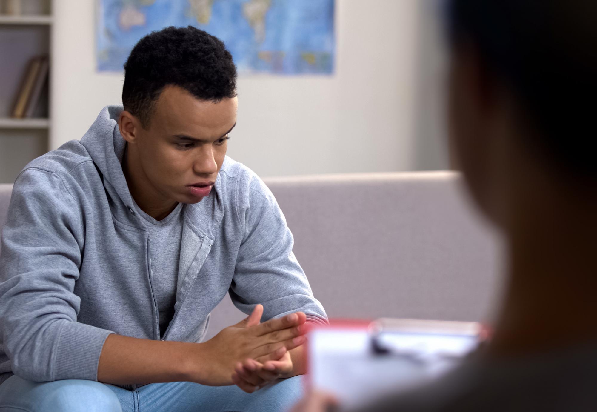 Male teenager discussing his mental health during therapy session