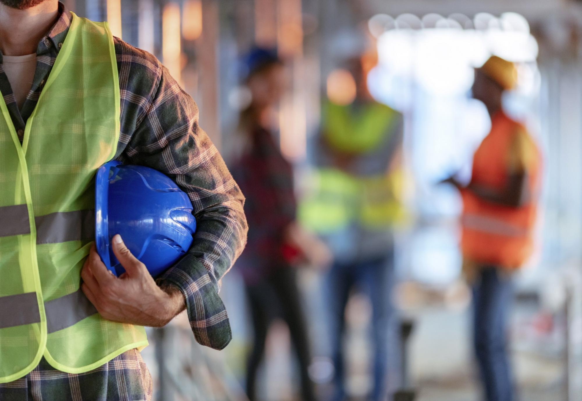 Workman holding hard hat tucked into elbow