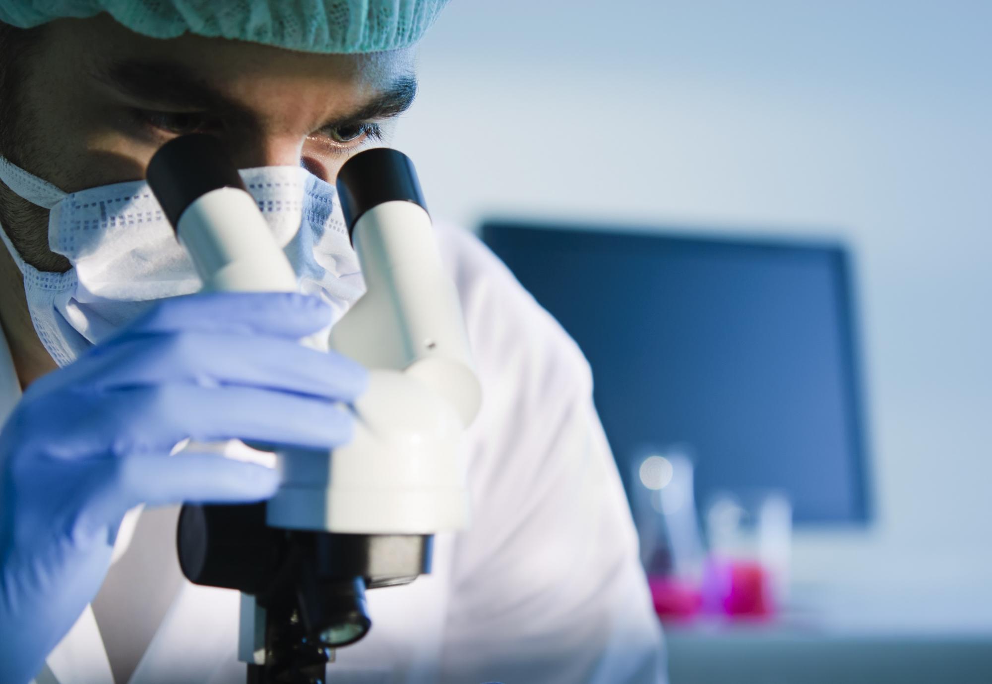 Male medical researcher using microscope