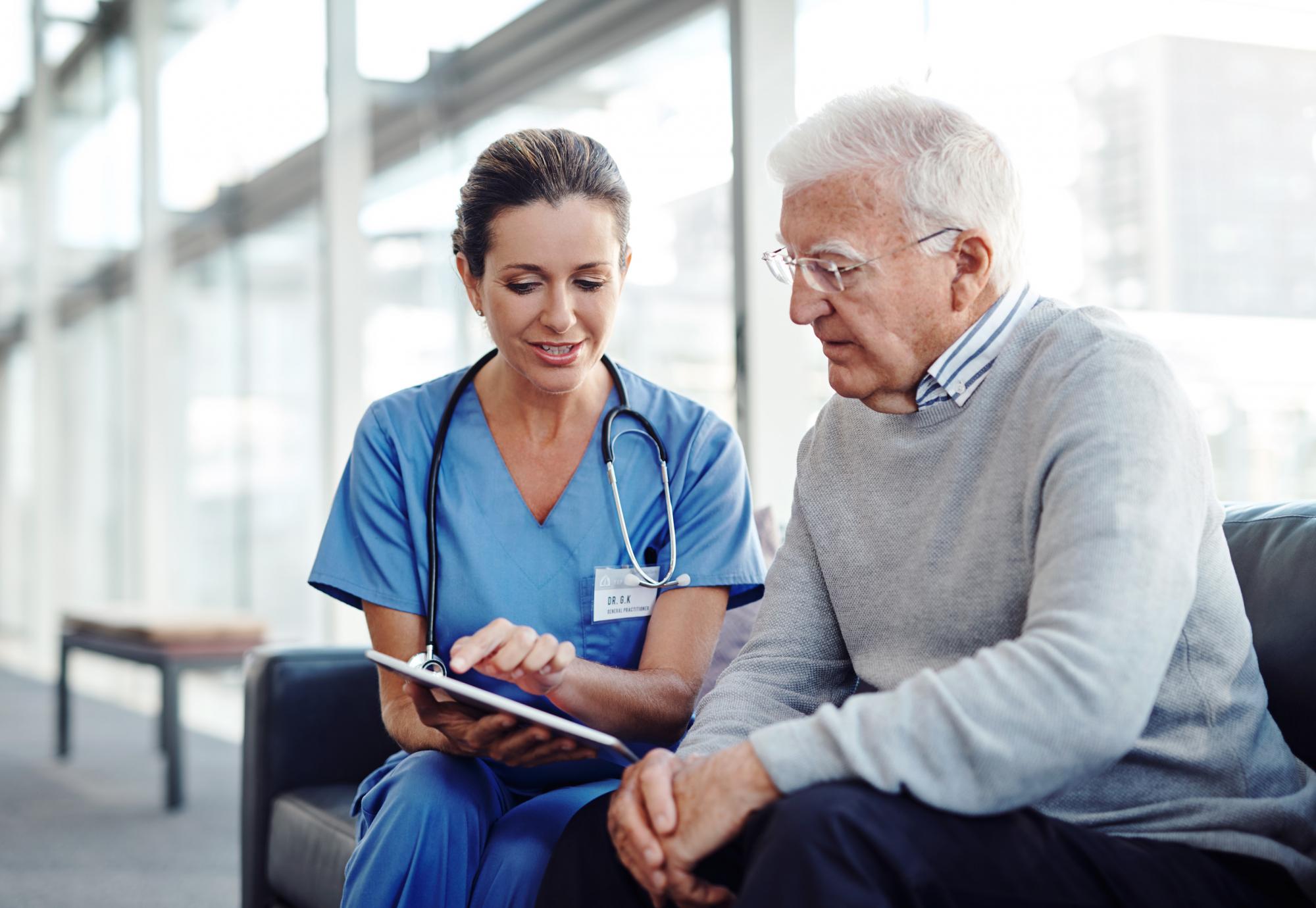 Female health professional with elderly patient using a tablet computer