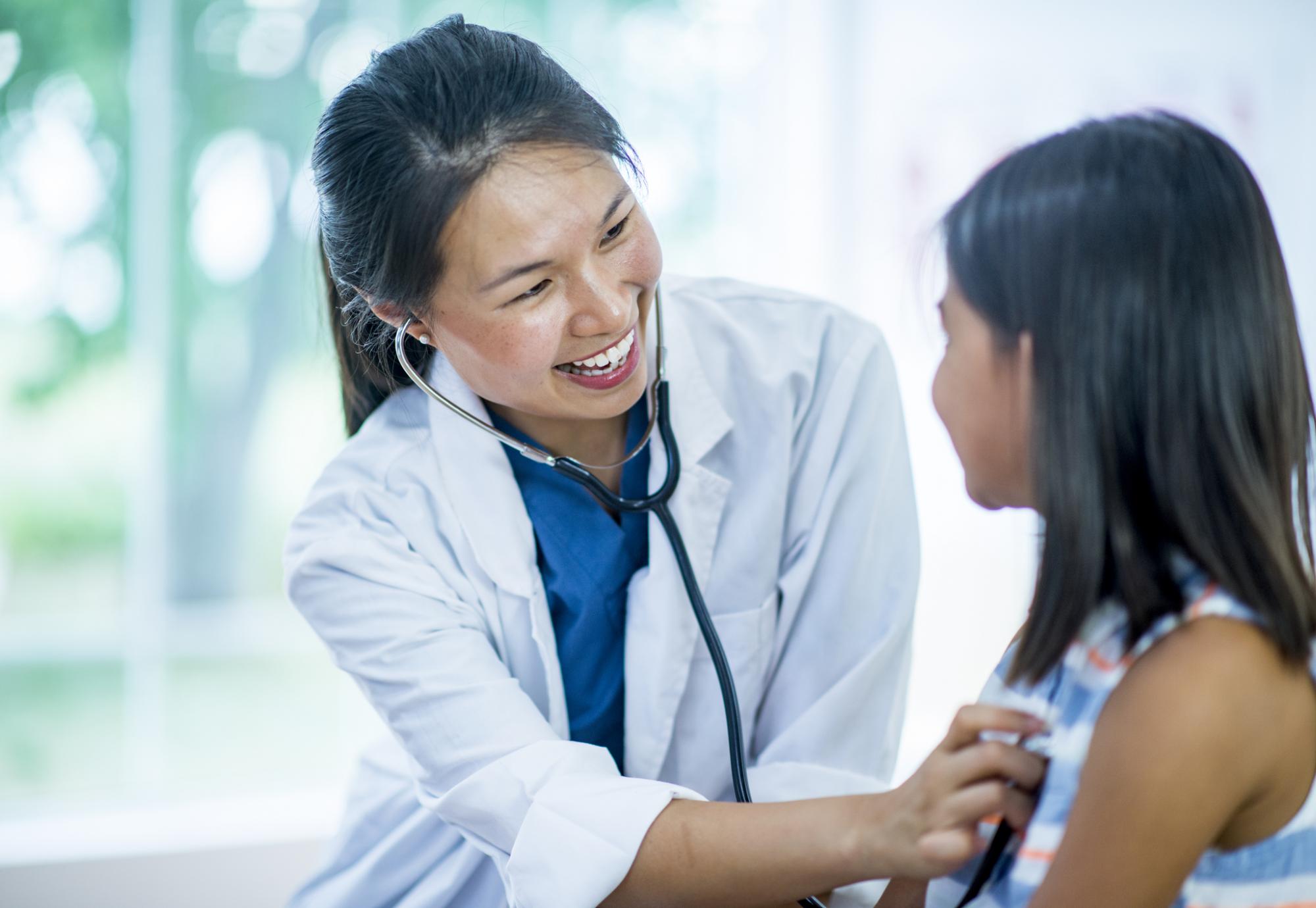 Female GP carrying out examination on young patient with stethoscope