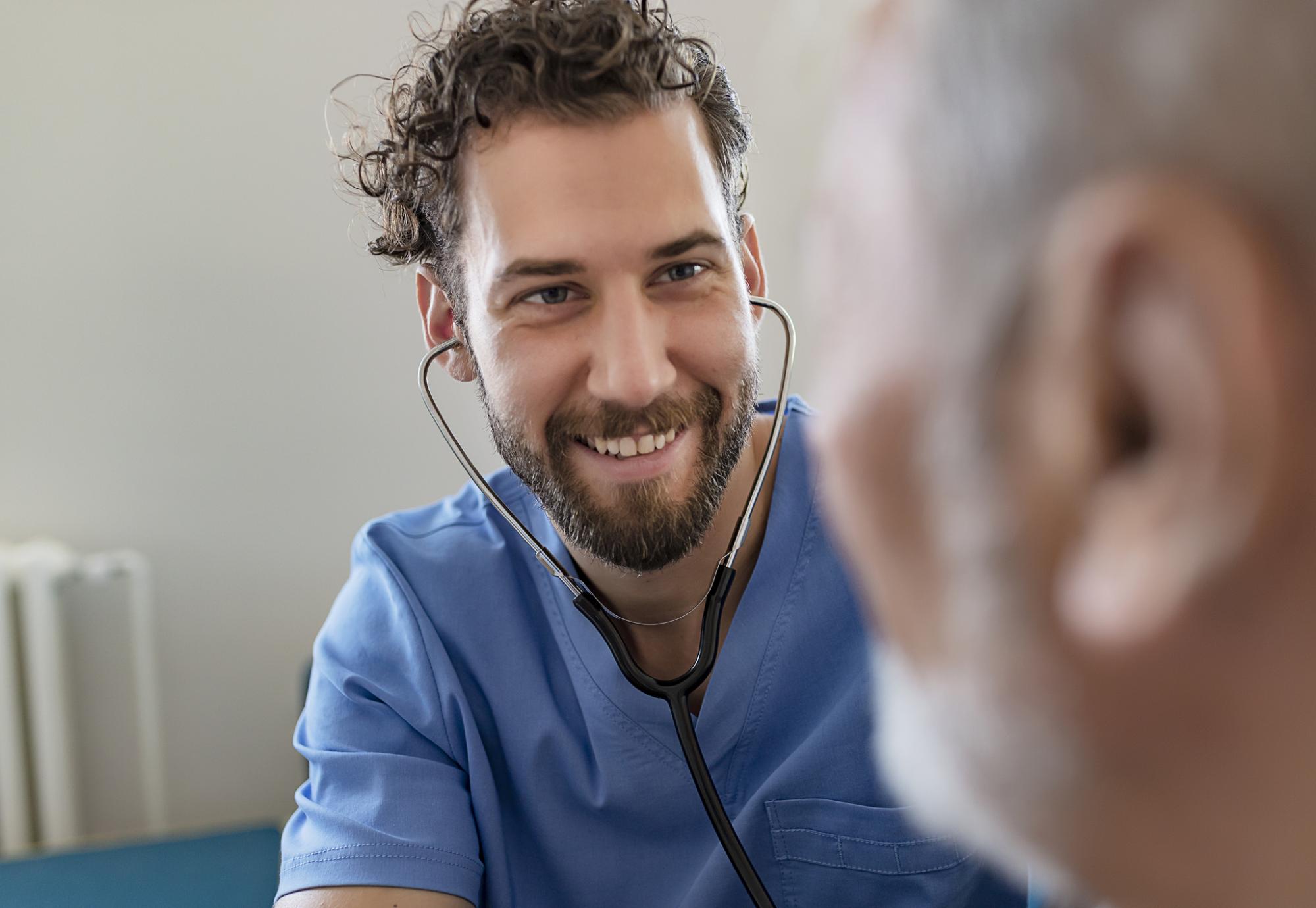 Male health professional listening to patient with stethoscope