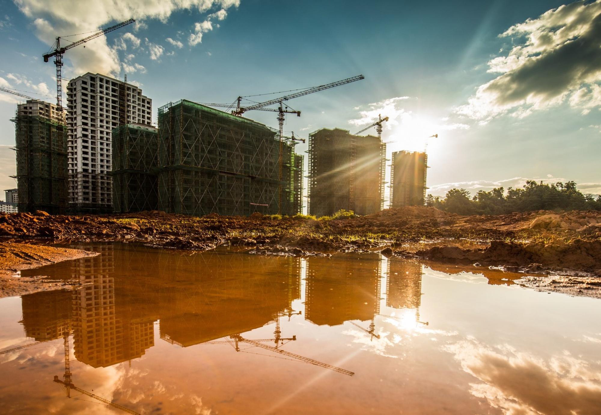 Construction site, with reflections off puddles on concrete in foreground