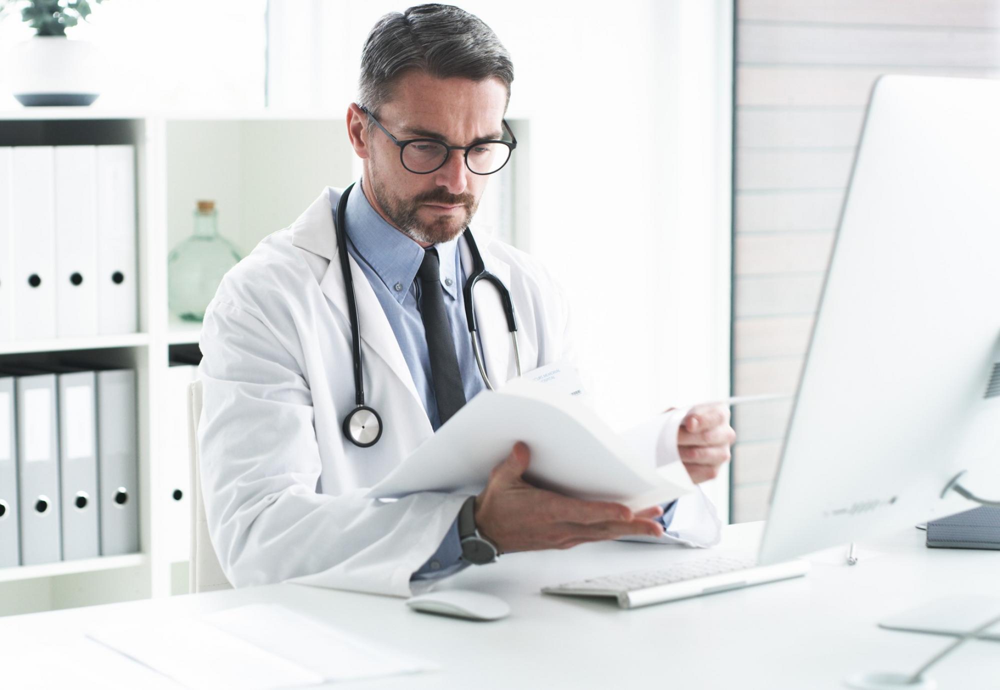 Male doctor reviewing paperwork at his desk