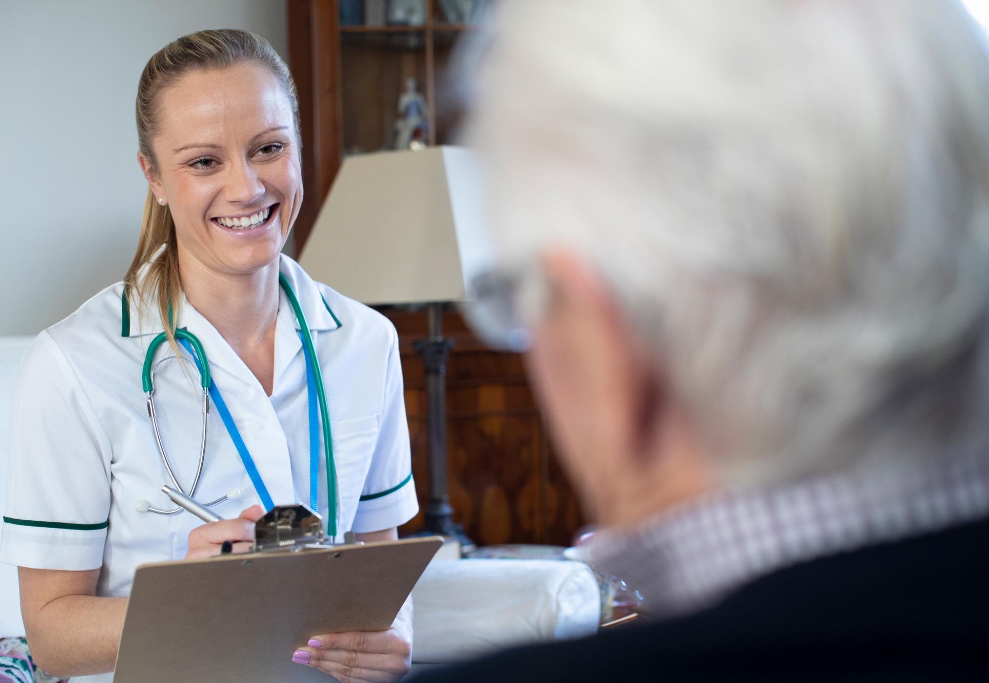 Female nurse recording information while interviewing a patient