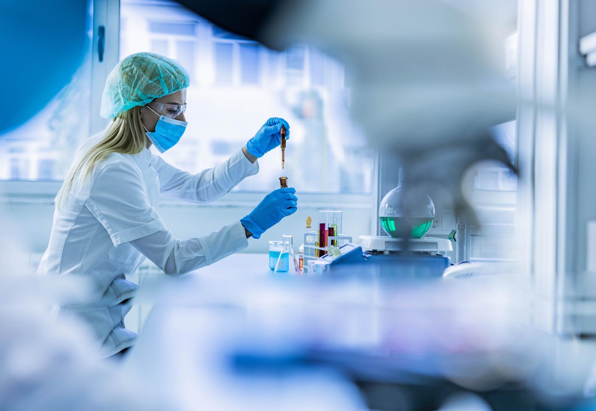 Lab technician working; soft focus photo through lab equipment