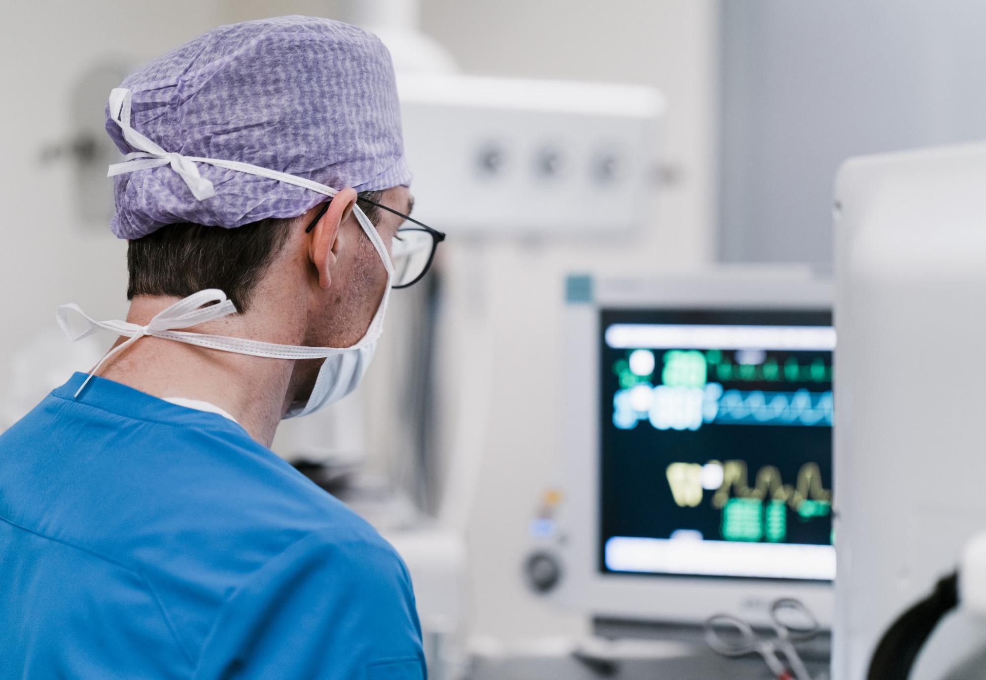 Male surgeon looking at a computer while in theatre