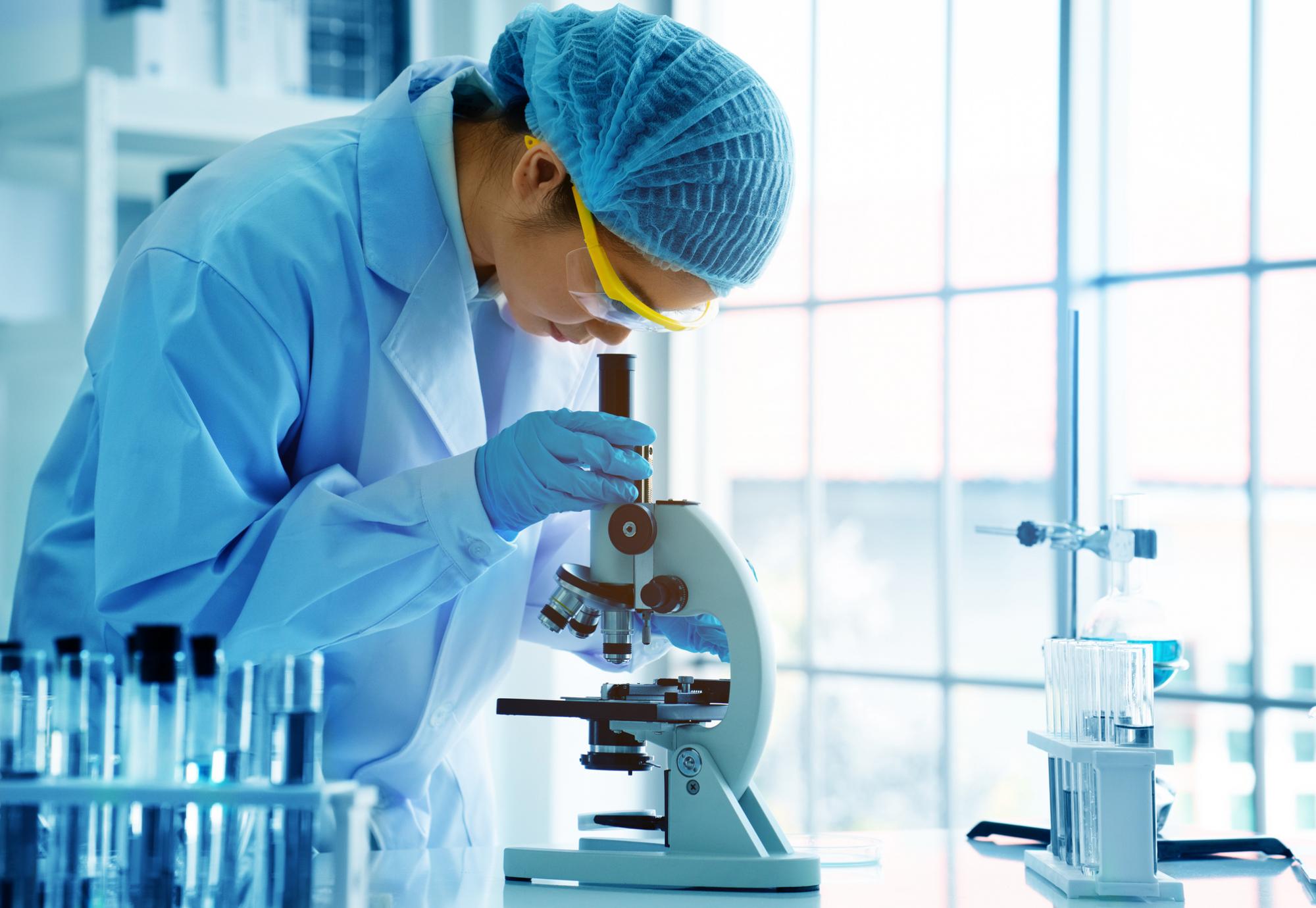 Female scientist looking into a microscope in a lab