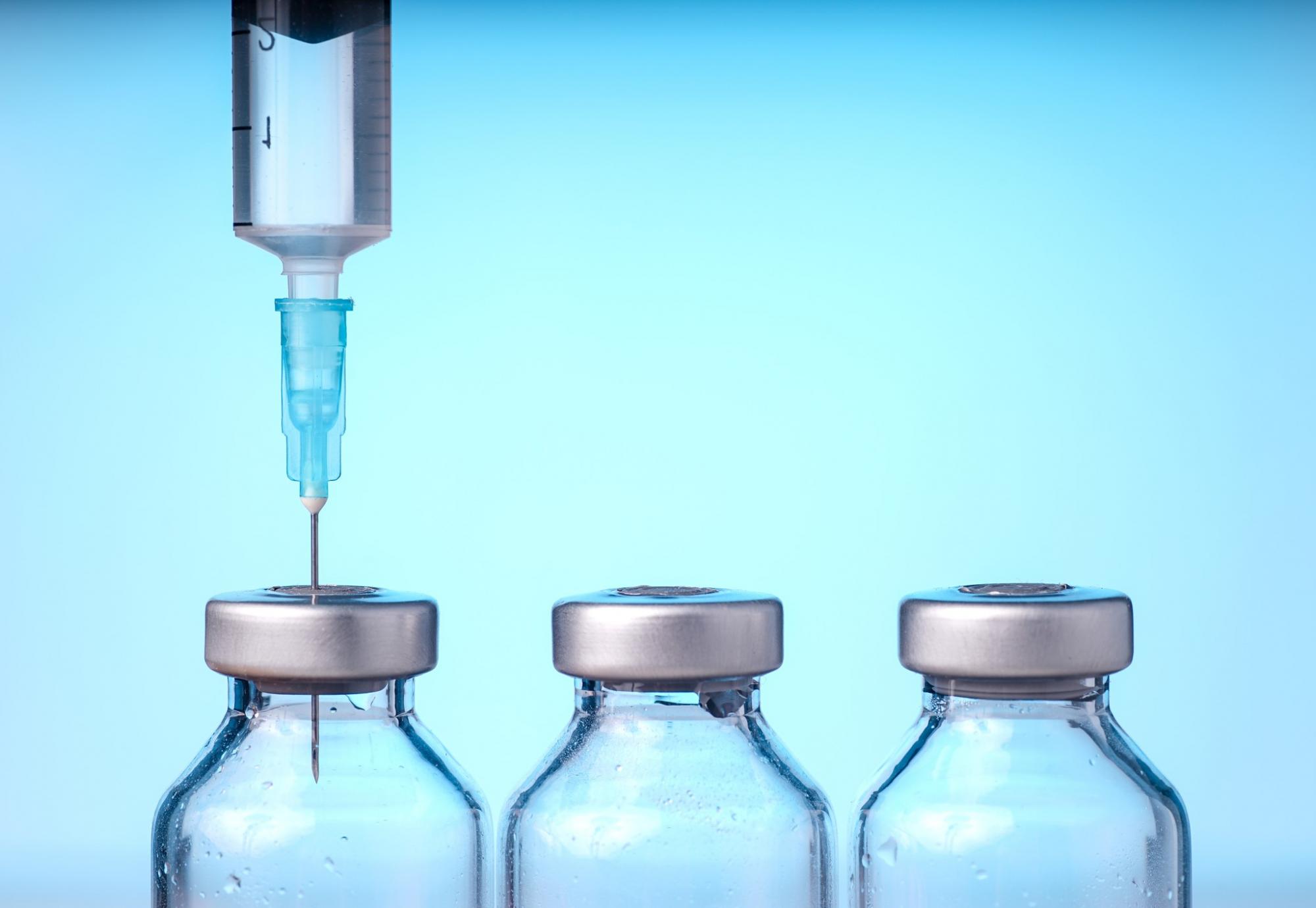 Needle injecting into the top of vaccine bottle