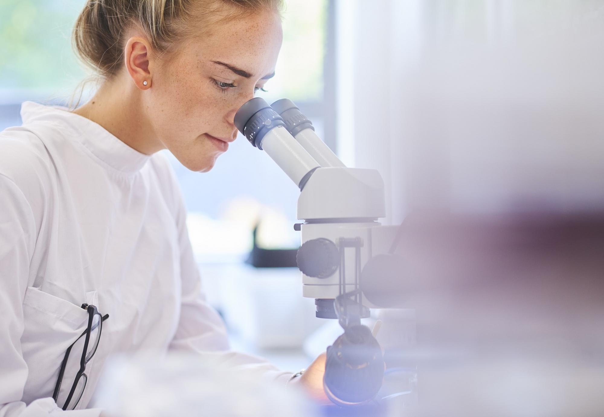 Female lab technician observing a slide in a microscope