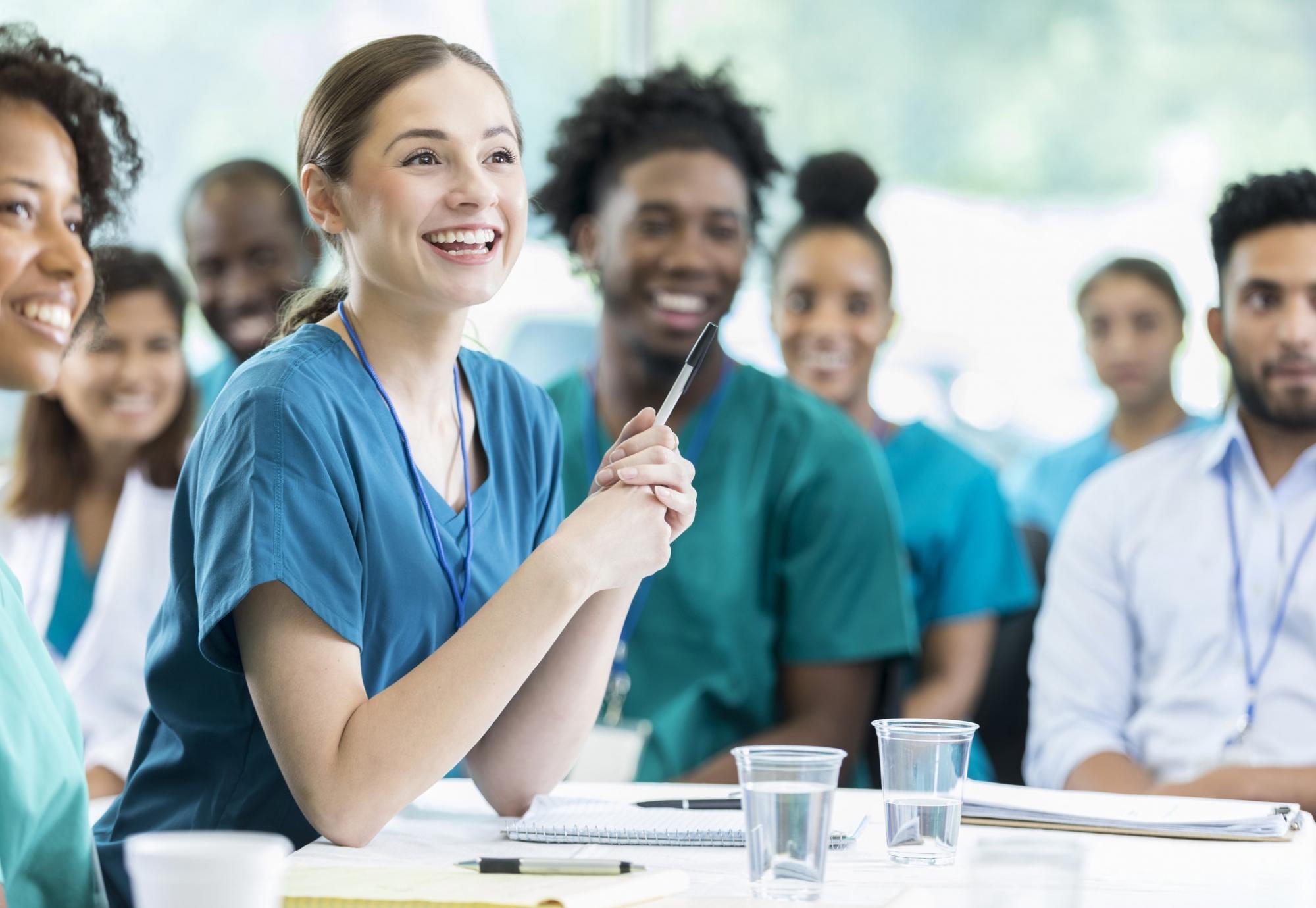 Female student nurse listening intently among a group of students