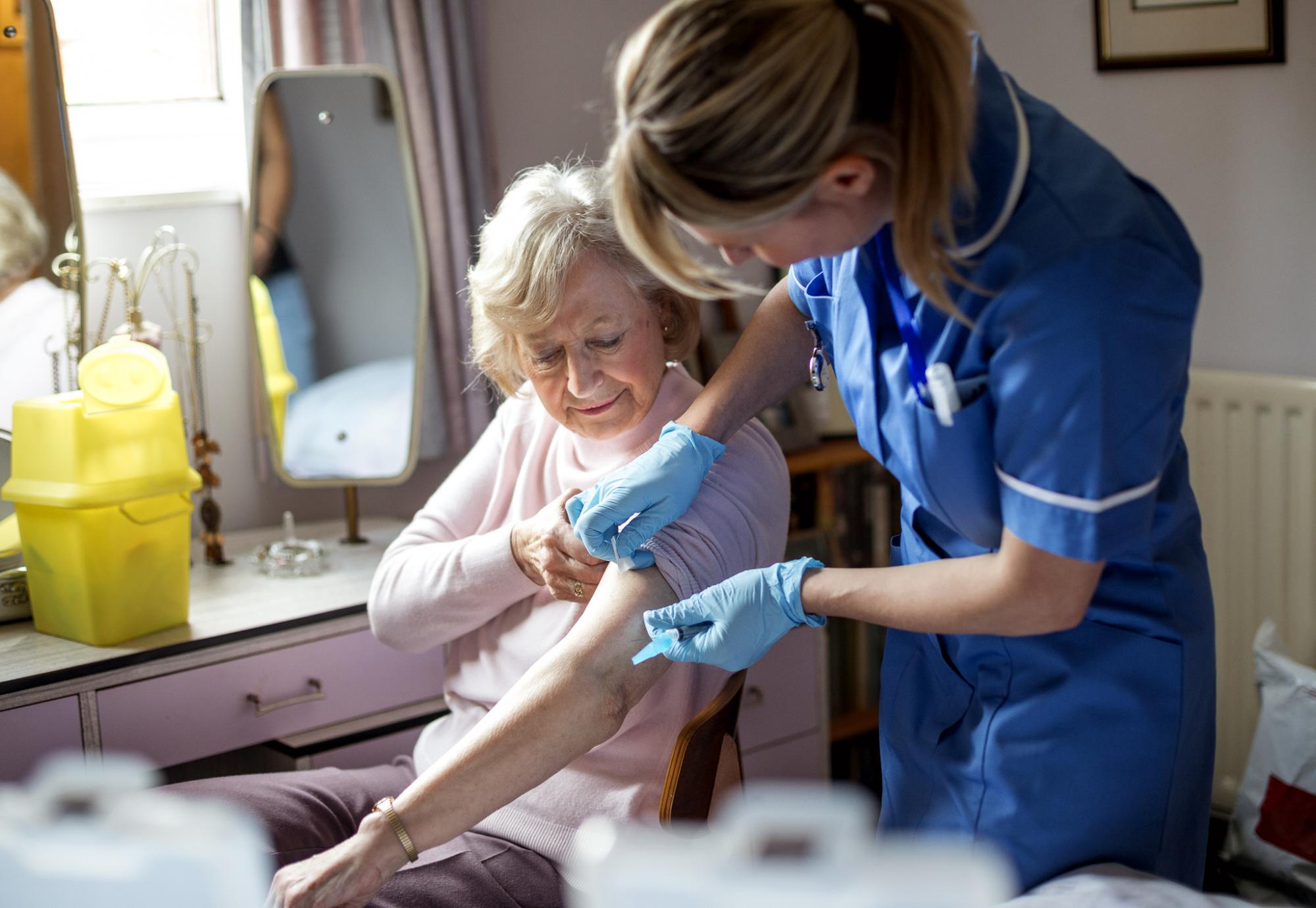 Community nurse administering a vaccine to an elderly woman