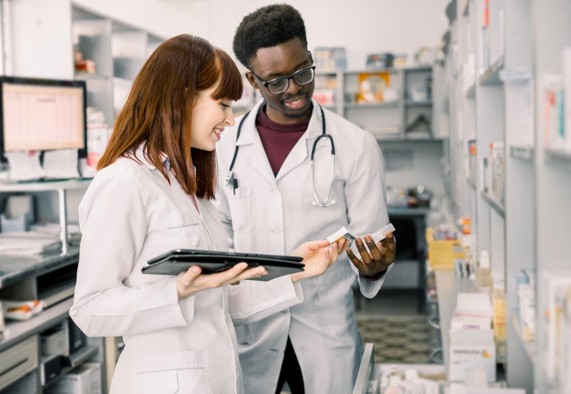 Two pharmacists reviewing a drug from their shelves