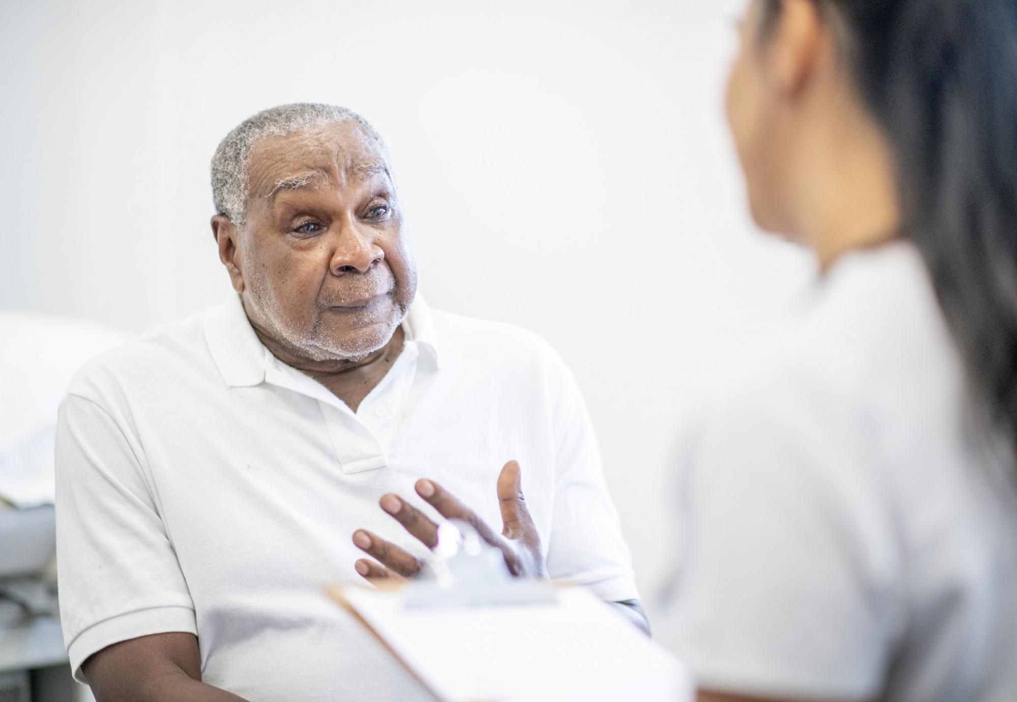 Elderly male patient discussing symptoms with a health professional
