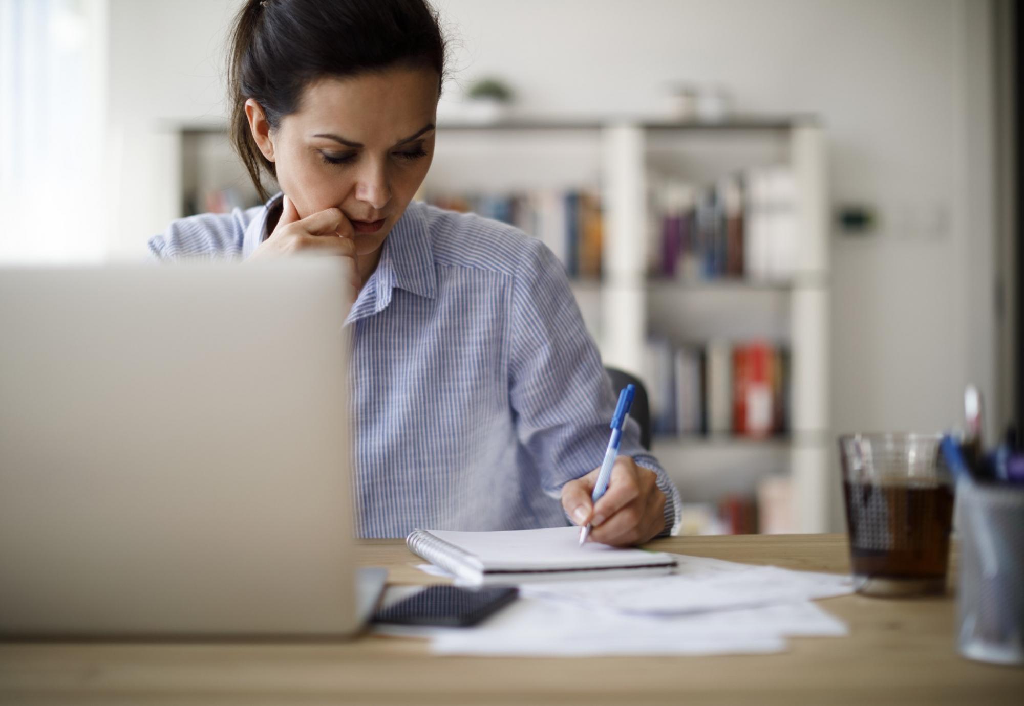 Woman making notes as she goes through e-learning materials