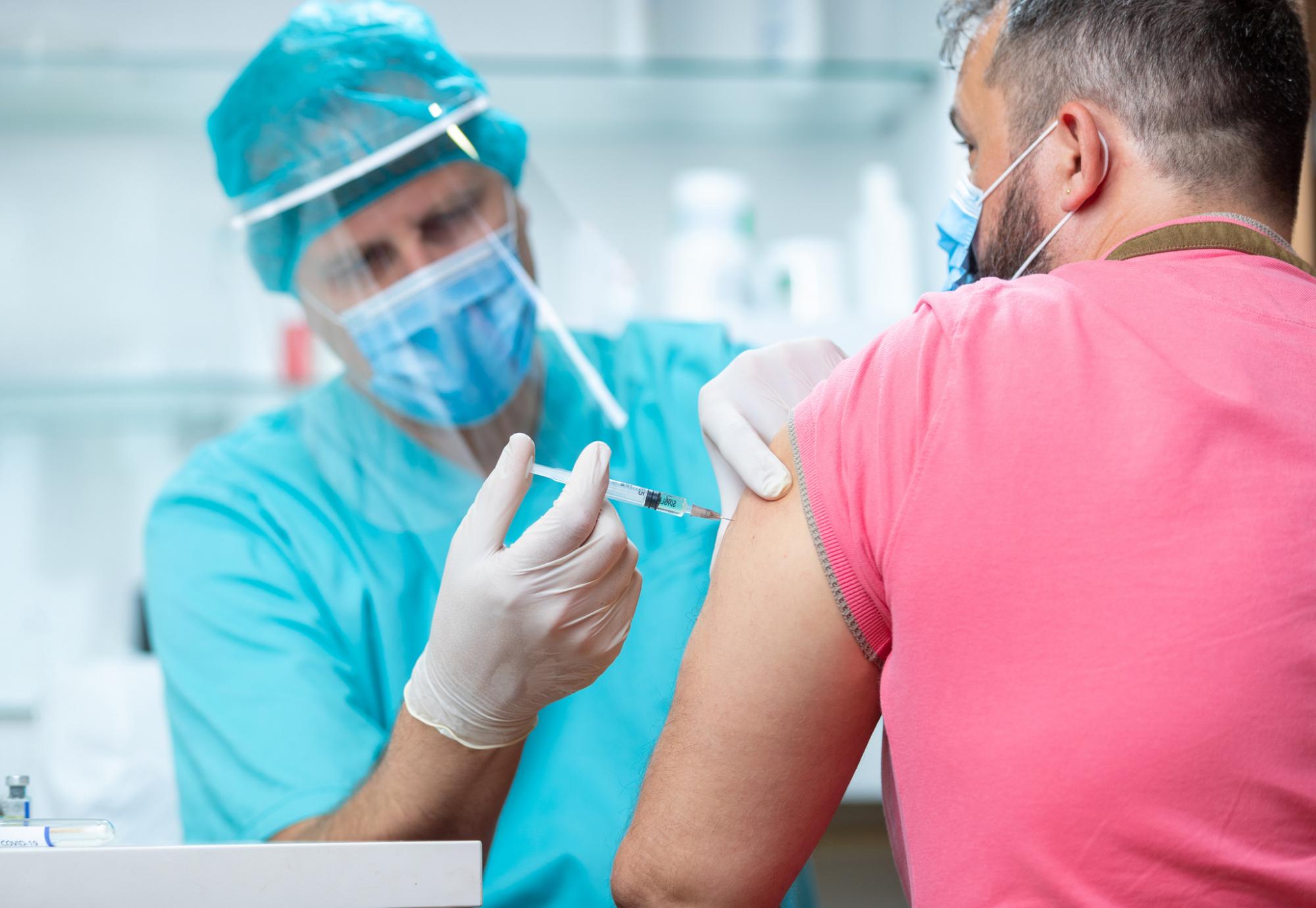 Health professional in PPE administering a vaccine jab