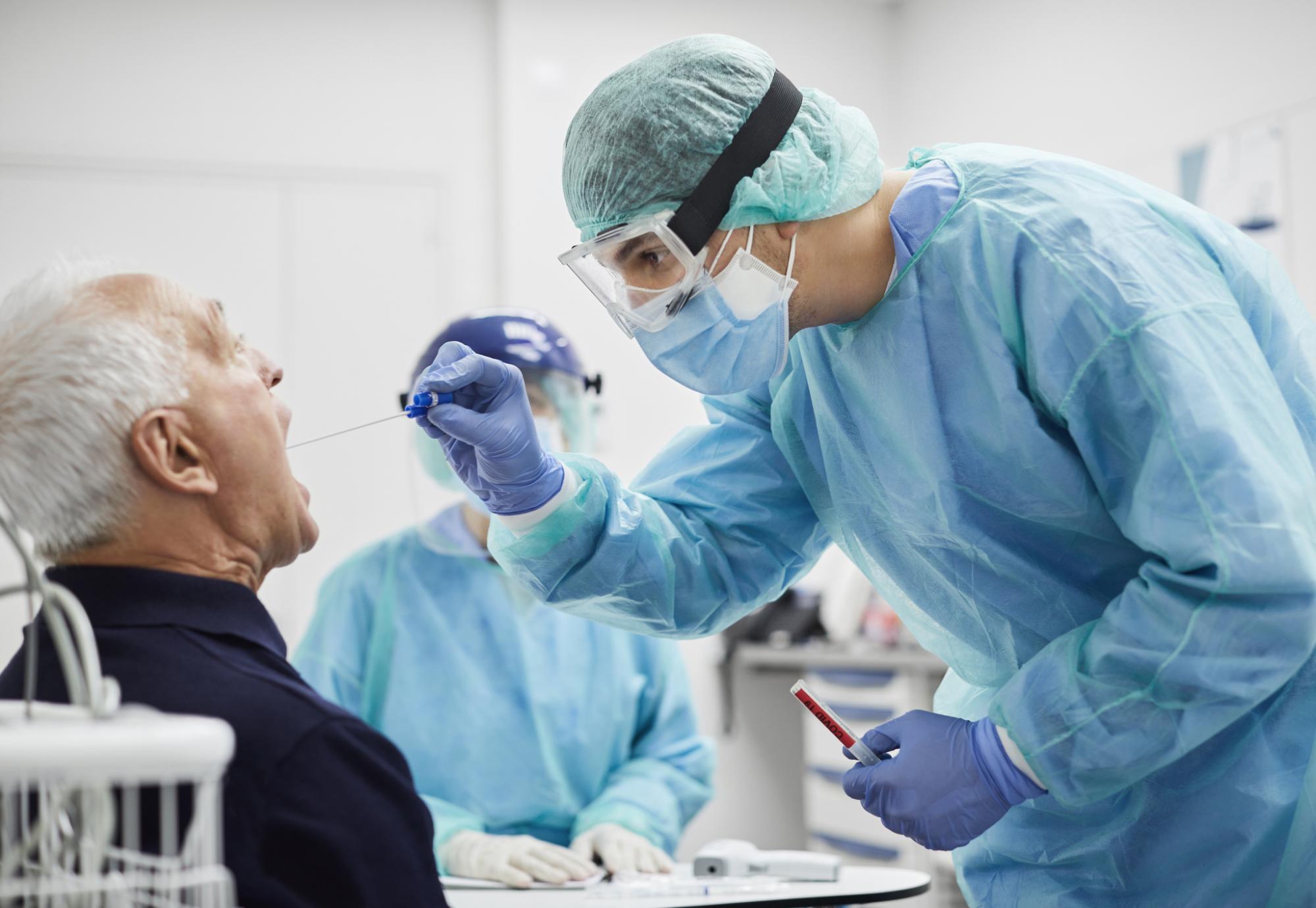 Male patient receiving a throat swab from a medical professional