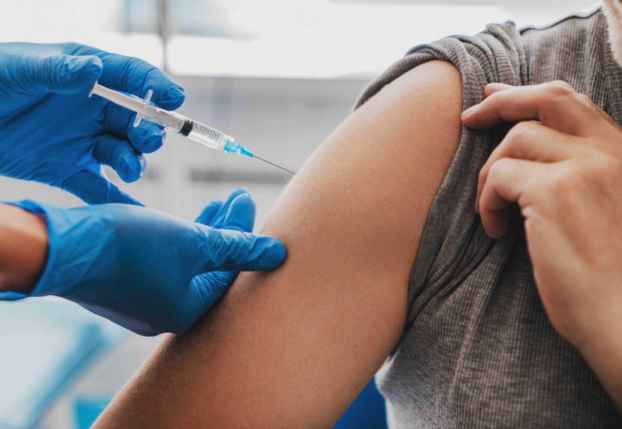 Health professional in gloves administering a vaccine jab