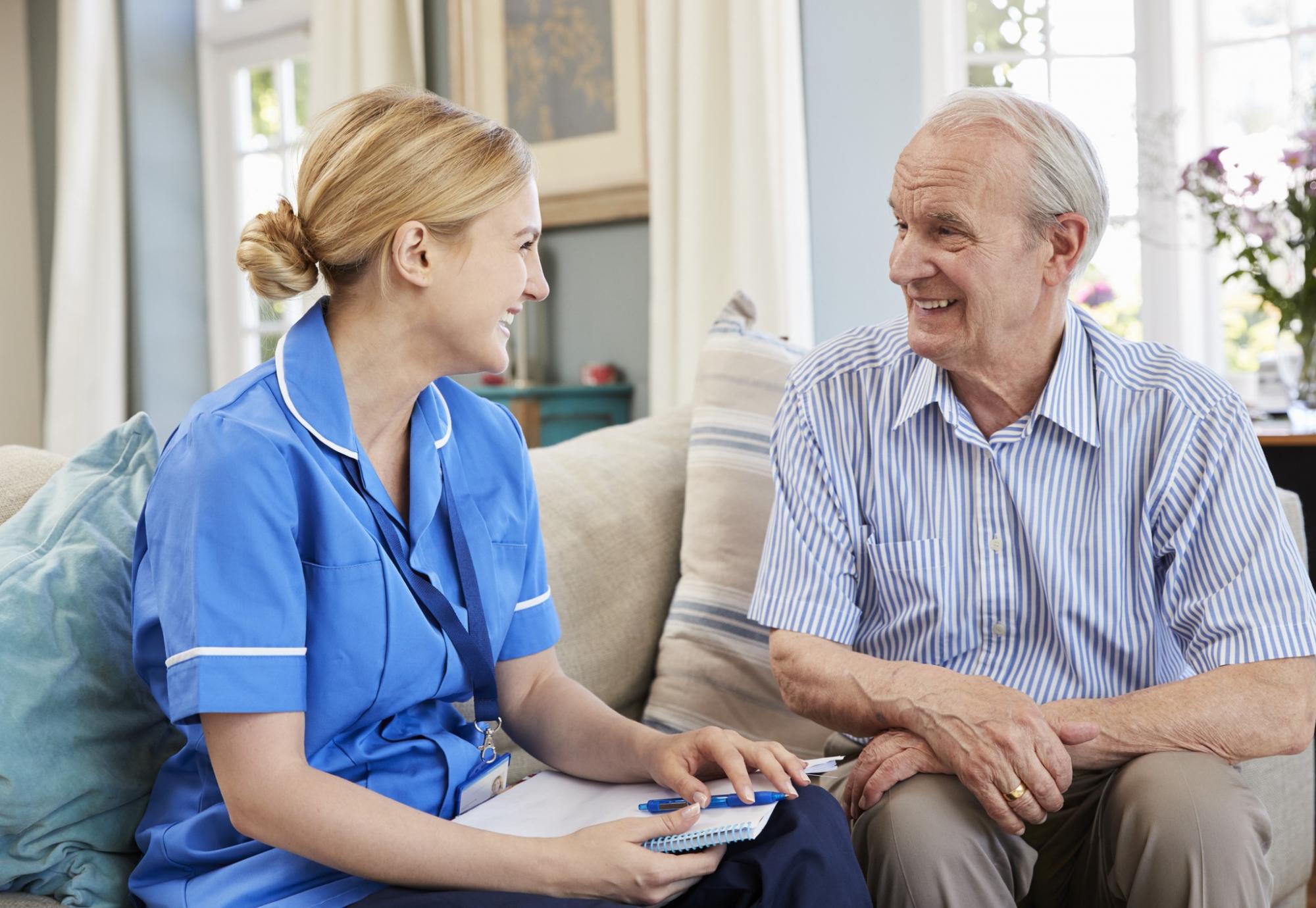 Female social care nurse sitting with an elderly man